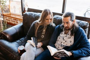 Cozy scene of reading together on leather couch in industrial-style room.