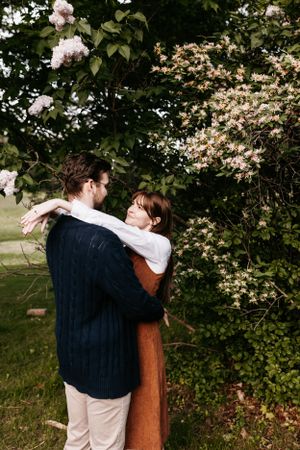 Romantic embrace among blooming spring flowers and trees in garden setting.