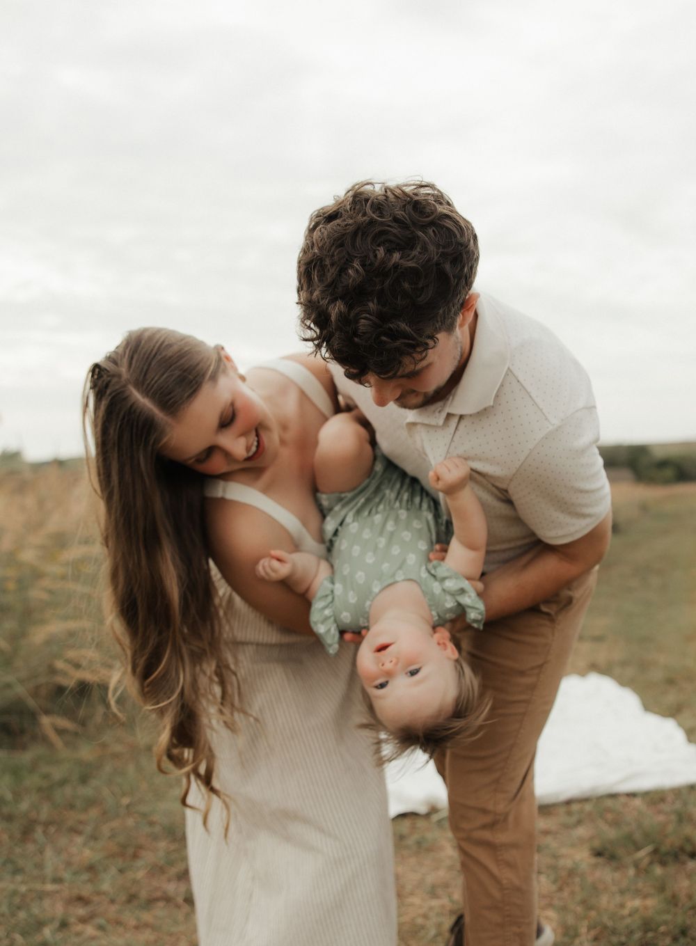 A family shares playful moments together during a golden hour photoshoot in a natural outdoor setting.