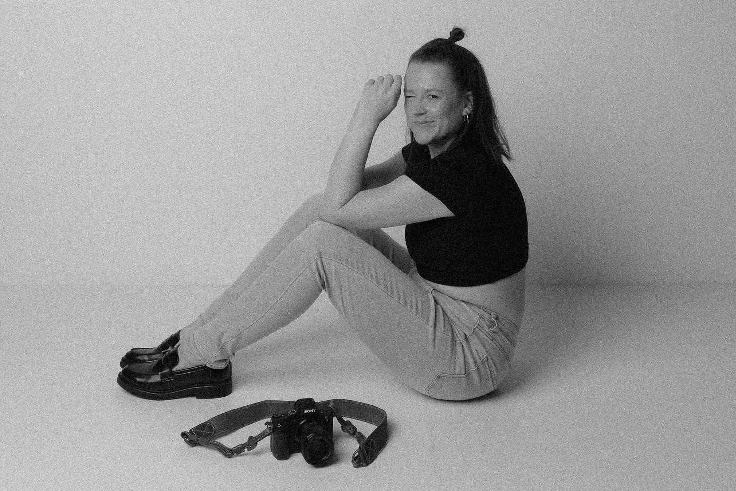 Zwinkernde Fotografin mit Kamera vor ihr liegend in Dresden