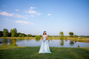 Wedding photography session by a scenic lake with blue skies and green landscape.