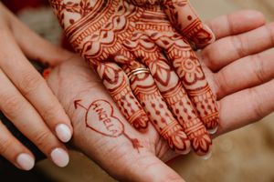 Close up of intricate henna design on palm featuring hearts and traditional patterns.
