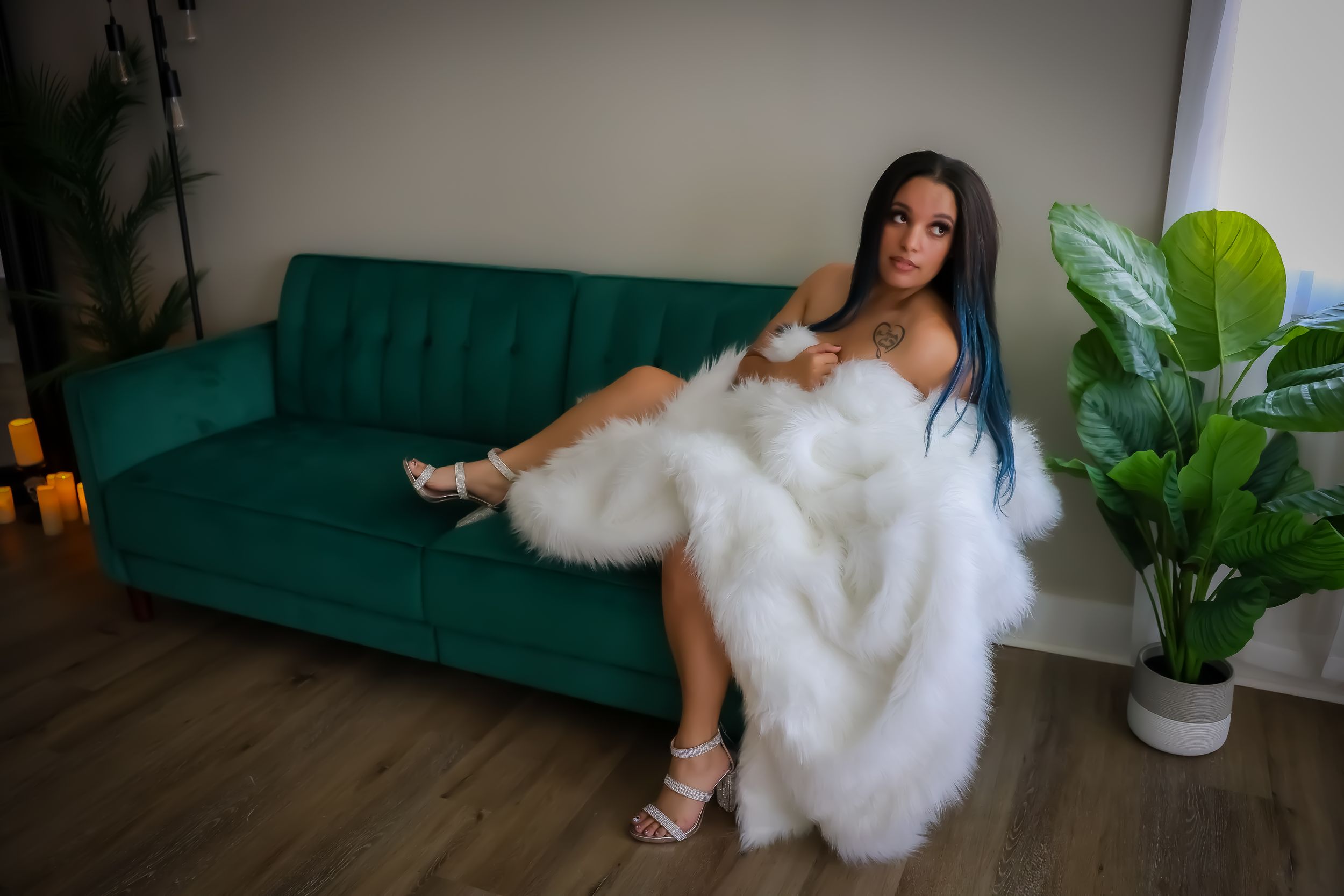 Elegant boudoir session with white fur accents on emerald green couch.