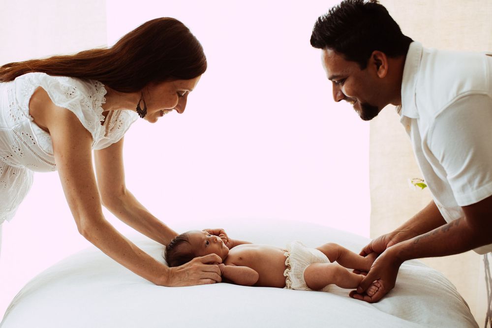 Tender moment between parents and newborn baby during intimate lifestyle photoshoot.