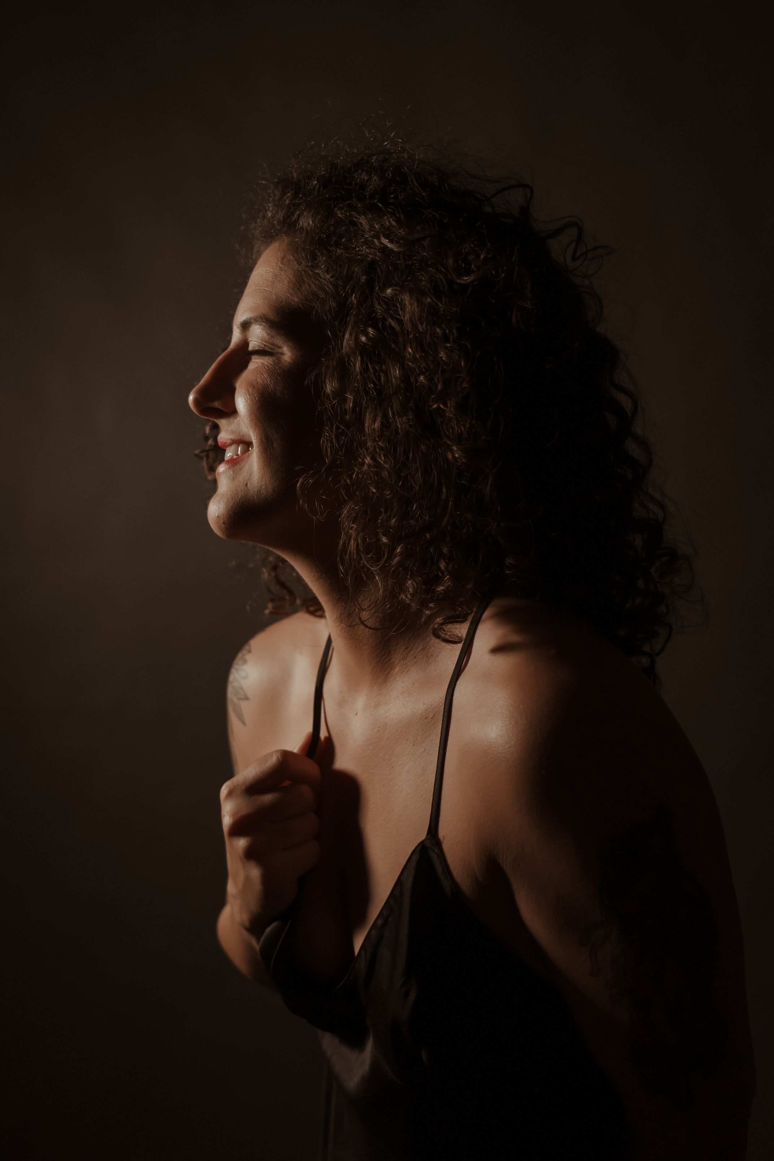 Artistic black and white portrait series showing silhouetted figure with curly hair against dark background in dramatic lighting.