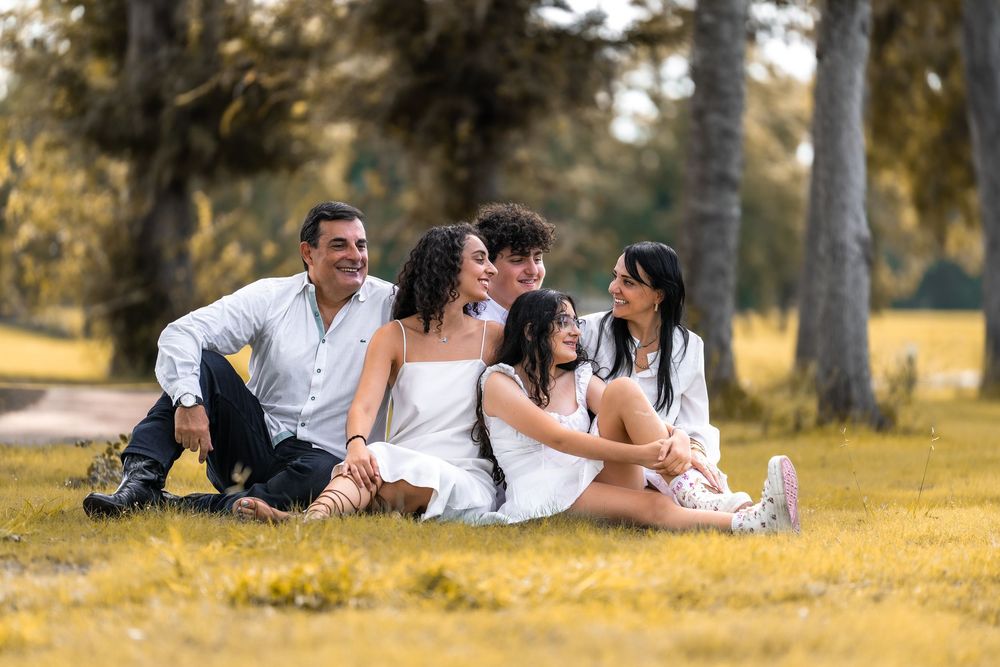 Couple in white clothing lying on yellow grass in autumn park setting during romantic photoshoot.