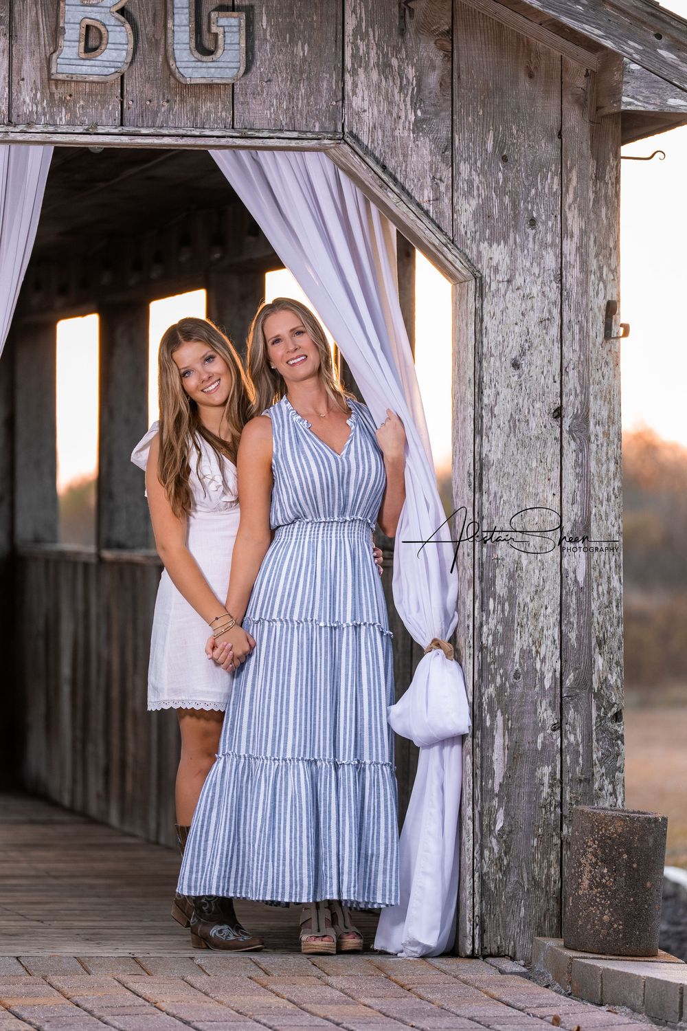 Rustic barn photoshoot featuring blue and white striped dresses against weathered wood walls.