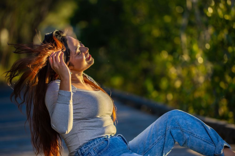 Person with flowing hair poses playfully on wooden walkway at sunset.