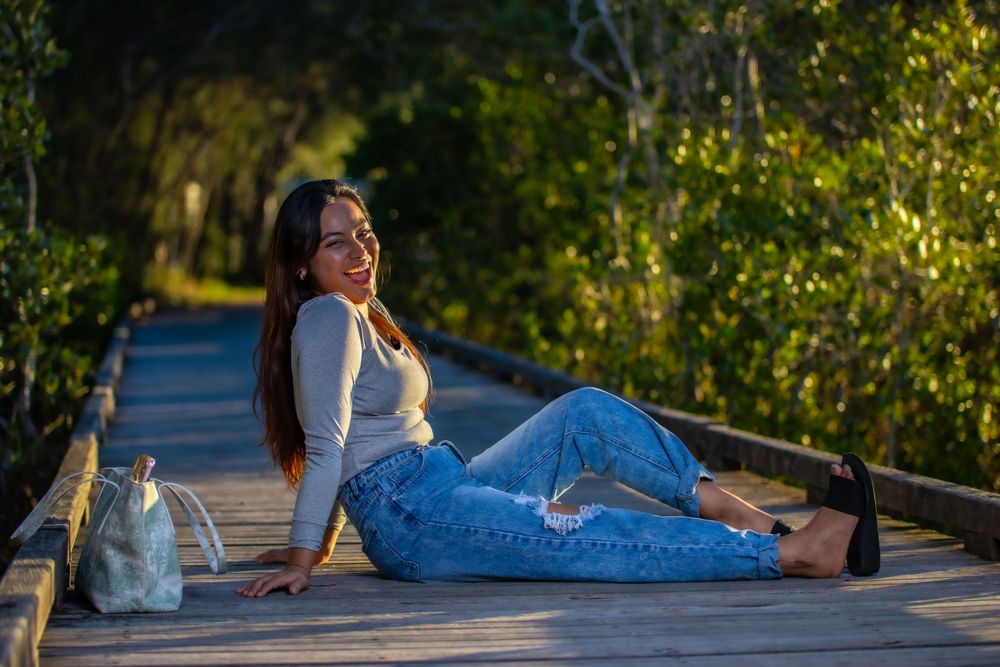 Casual portrait on wooden boardwalk with greenery and natural lighting.