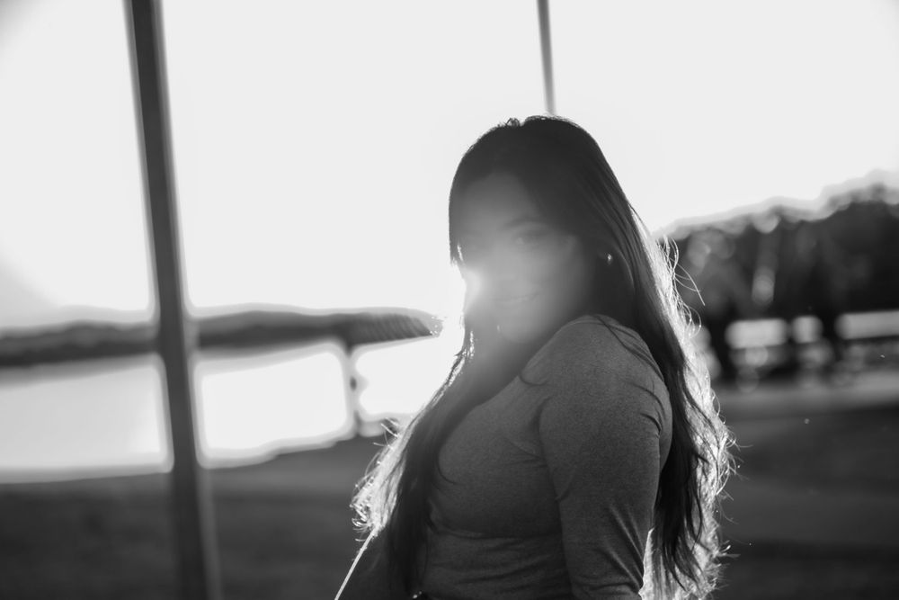 Silhouette portrait at sunset with backlit long hair creating a dreamy atmosphere on a boardwalk.