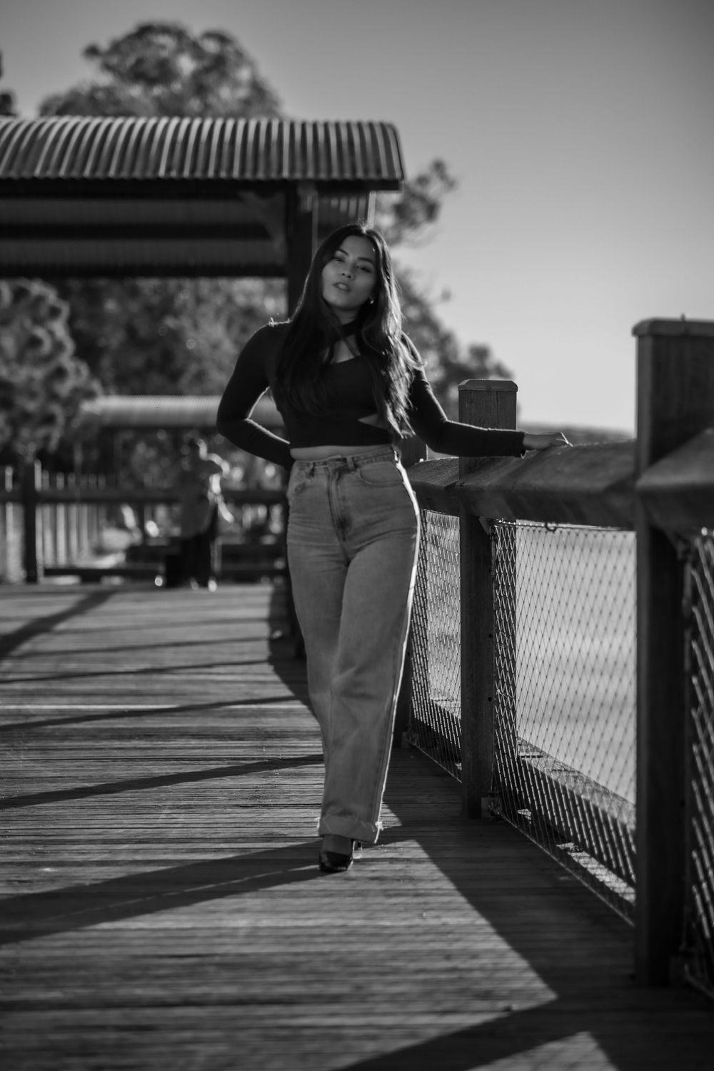 A fashion portrait taken on a wooden boardwalk with dramatic black and white lighting.