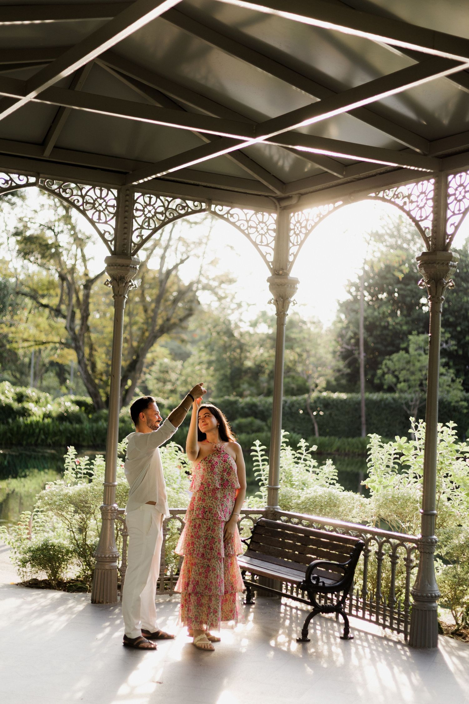 Romantic couple lounges on grass during outdoor photo session wearing floral dress and casual attire.