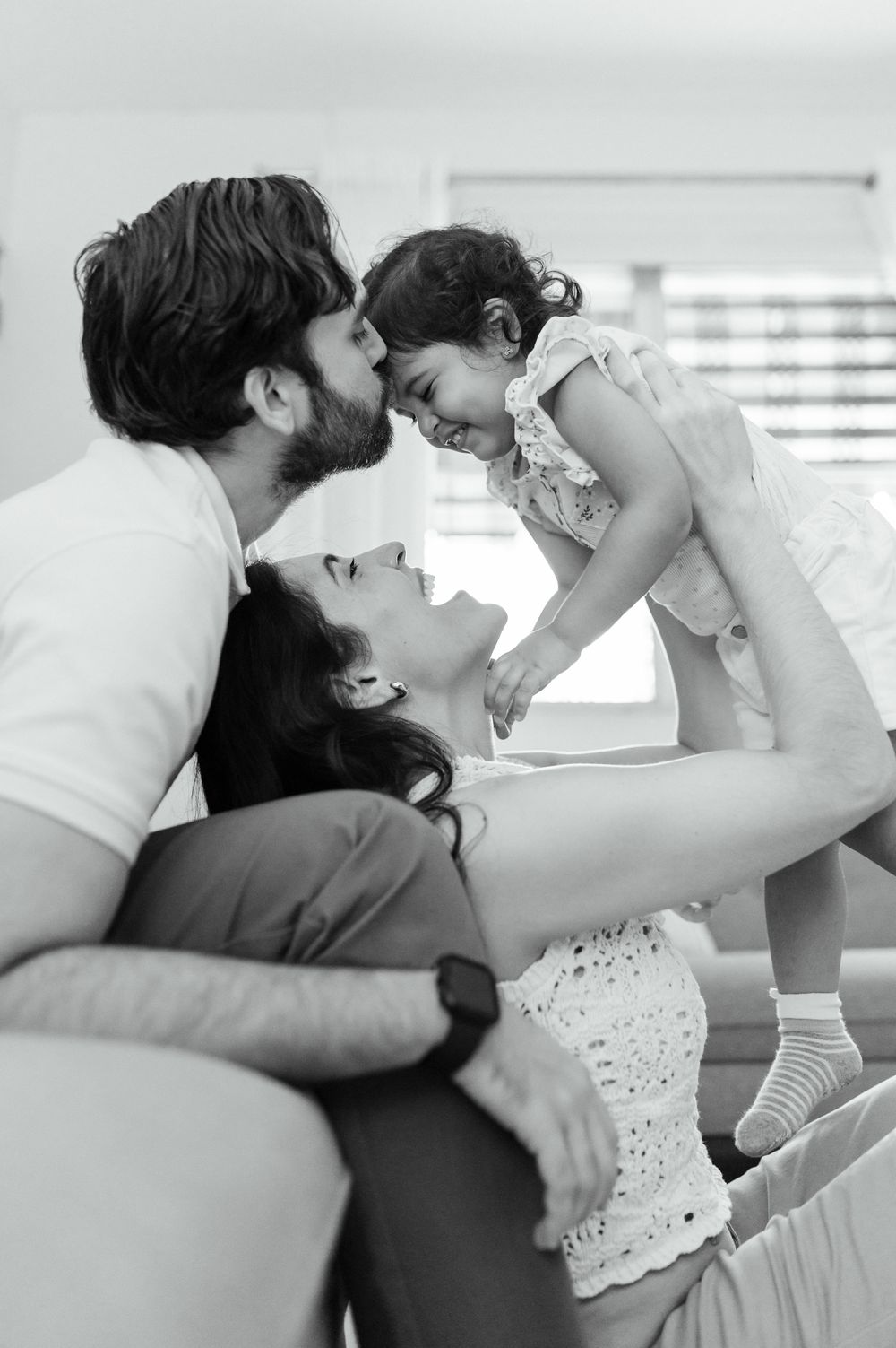 Intimate family moment captured in black and white on a couch.
