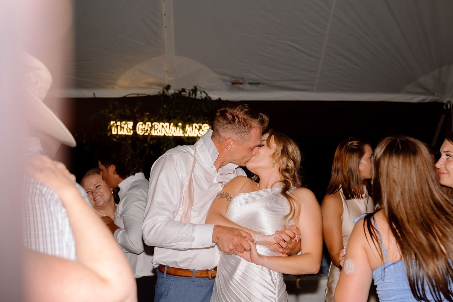 Wedding couple sharing romantic kiss during bubble sendoff at venue exit.