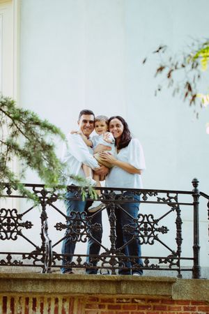 Family enjoying time together on a balcony with ornate iron railings.
