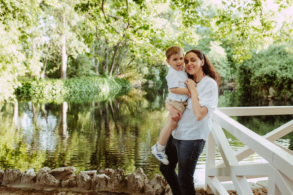 Family walking together near a peaceful pond surrounded by lush greenery.