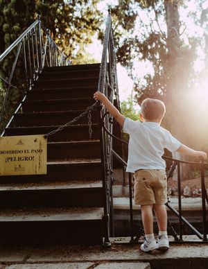 Small child climbing wooden stairs in a park during golden hour sunlight.
