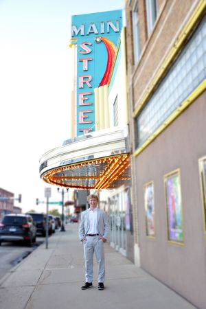 Person standing beneath vintage Main Street theater marquee sign with rainbow design.
