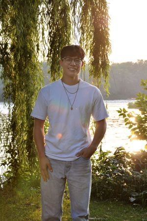 Portrait by willow tree at sunset with lake in background.