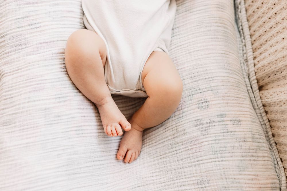 Sweet newborn baby sleeping peacefully on soft white bedding.