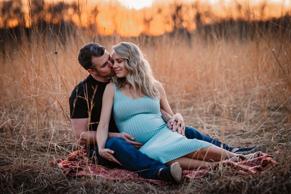 Maternity photo session in golden field during sunset with romantic pose.