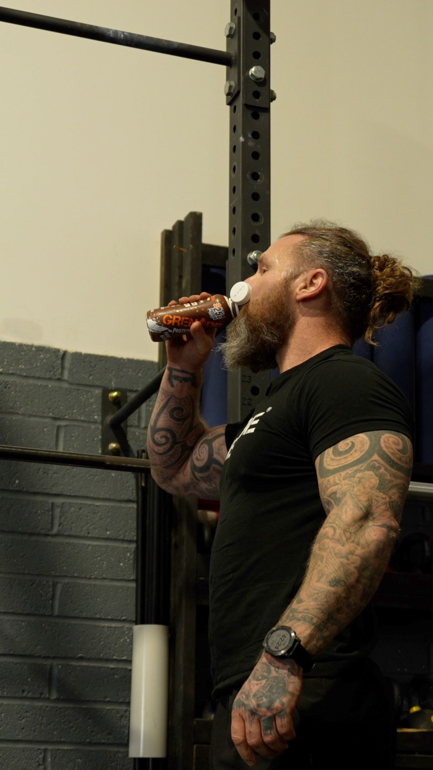 Athletic person in black shirt drinking from bottle during workout at gym.