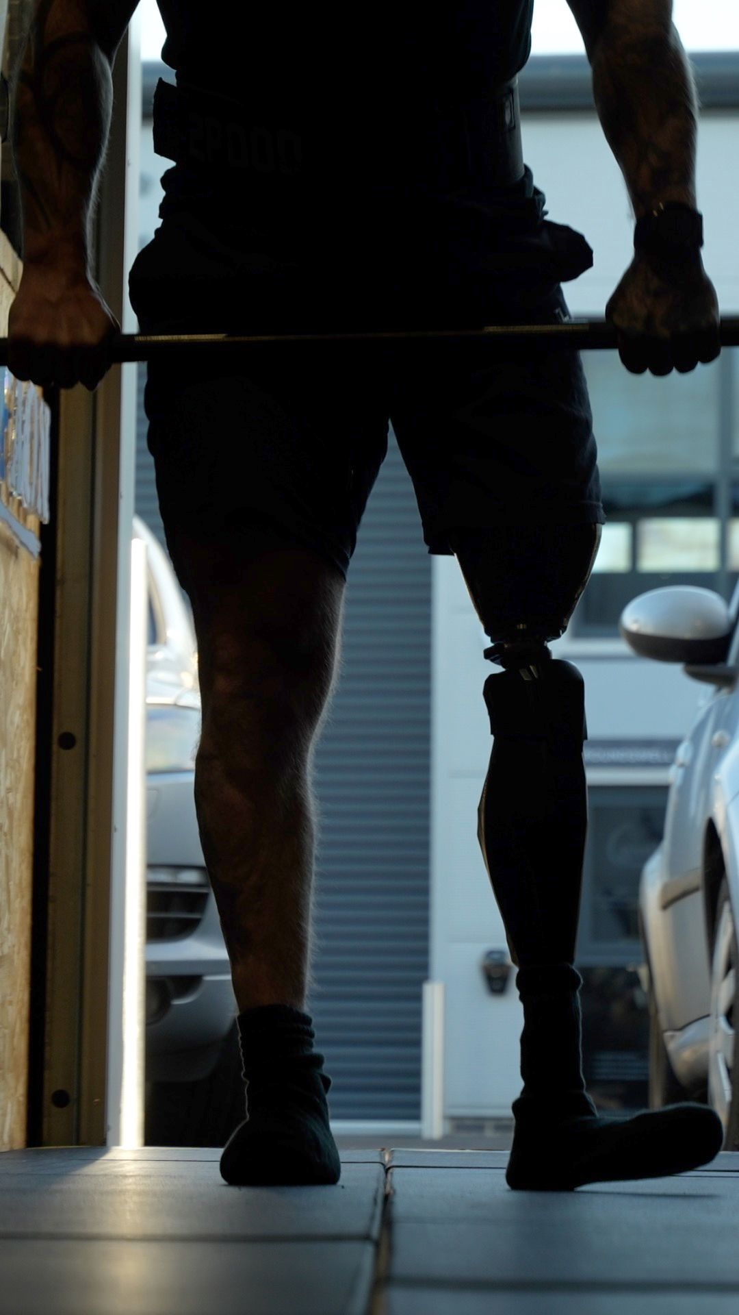 Silhouetted figure with prosthetic leg standing in doorway.