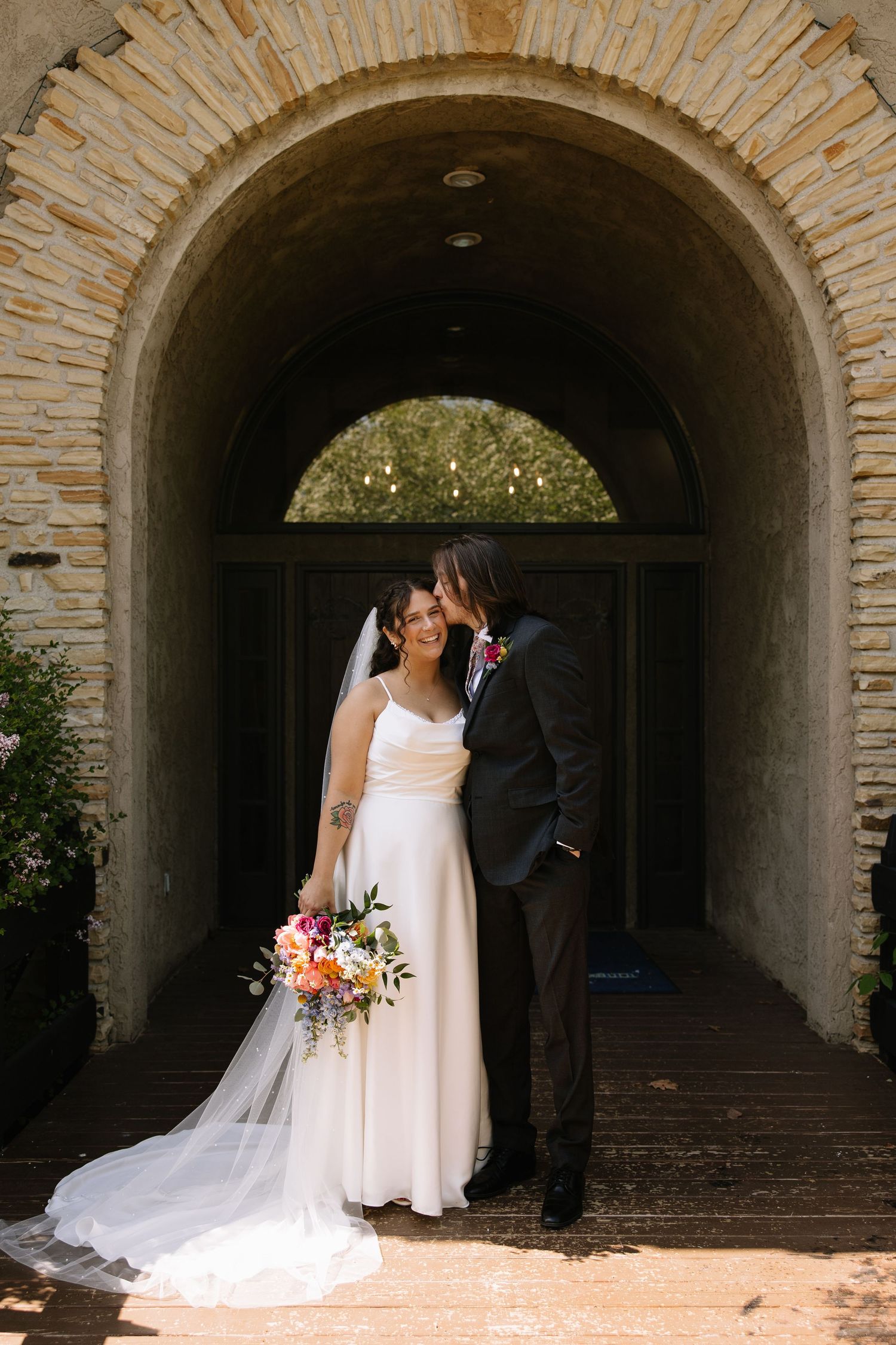 A romantic wedding portrait under a willow tree with a flowing veil.