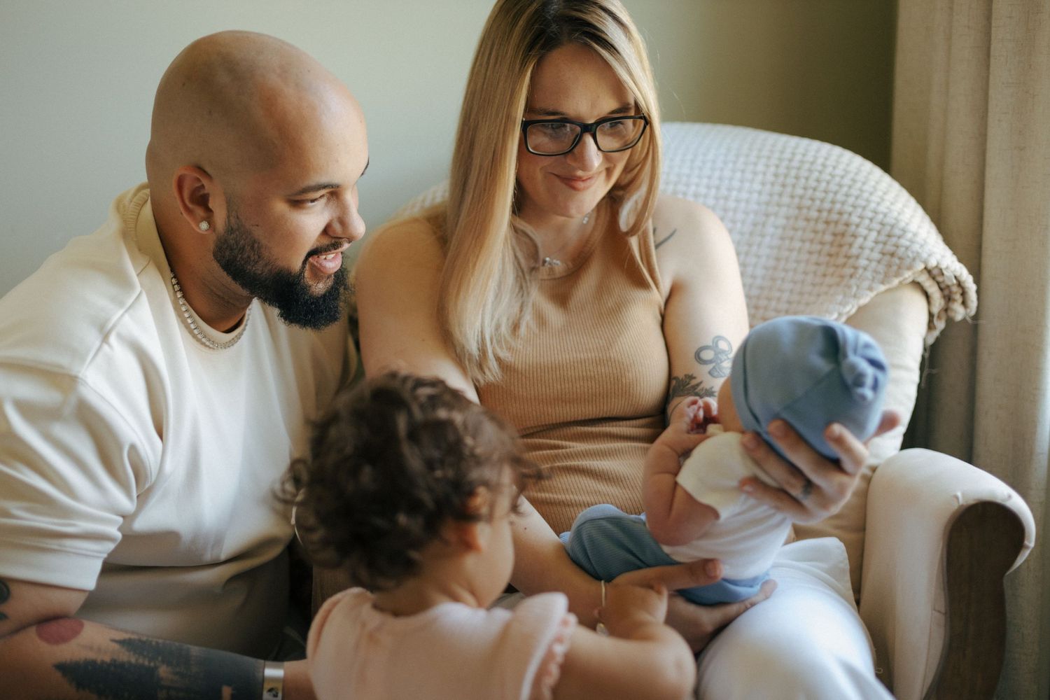 A family sits together on a couch in their living room having an intimate conversation.