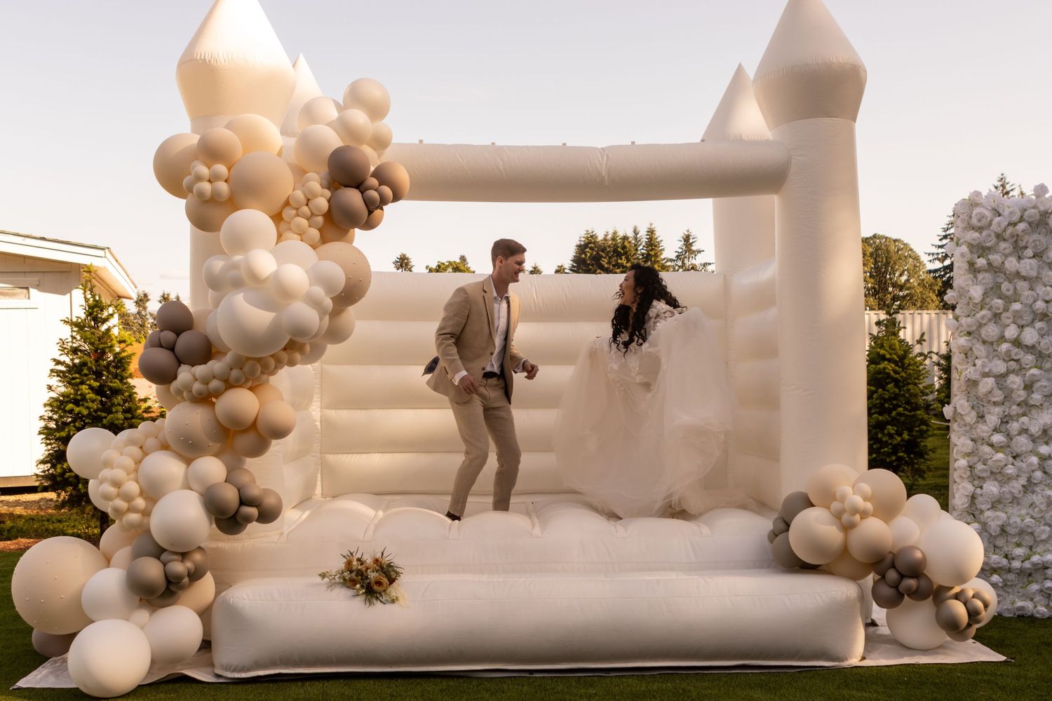 Interracial couple in white bounce house in wedding attire.