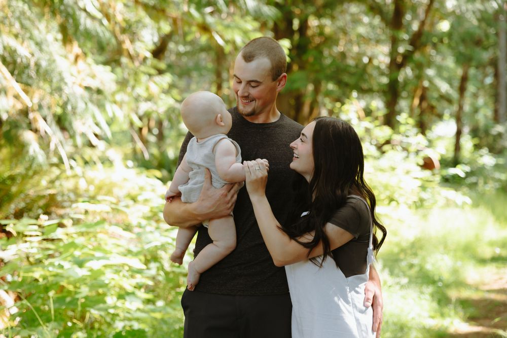 A joyful family shares a tender moment together while standing on a sunny forest path.