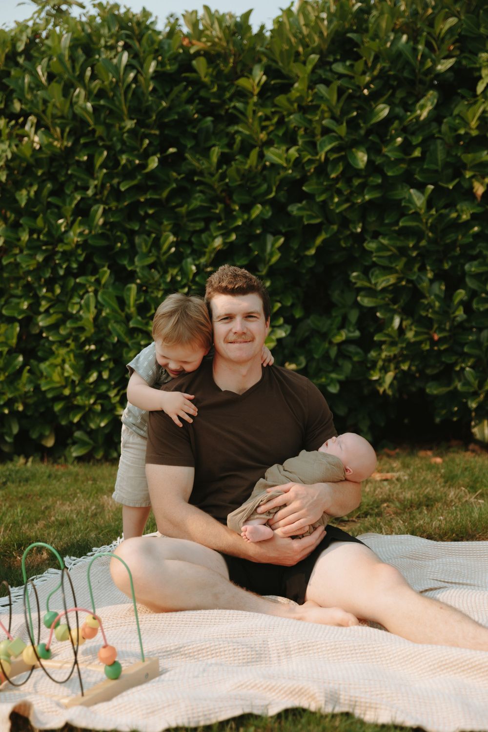 A relaxing outdoor picnic on a blanket with greenery in the background and a colorful toy on display.