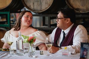 Bride and groom share a romantic moment at their head table in a barrel-lined winery venue.