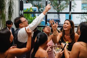 Wedding guests laugh and take selfies during a lively outdoor reception celebration.