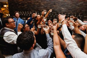 Wedding guests raise glasses in a joyful group toast at an intimate reception.