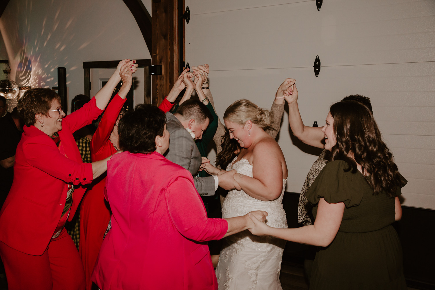 Bride and groom surrounded by loved ones on the dance floor at the reception.