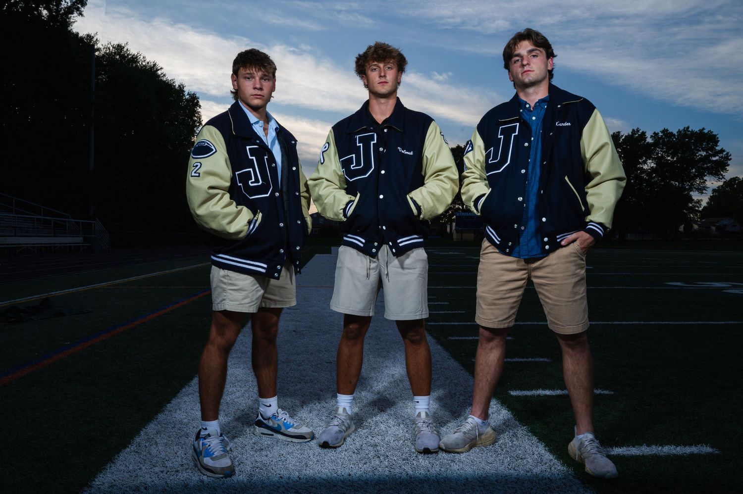 Team members line up on athletic field lines during evening photoshoot.
