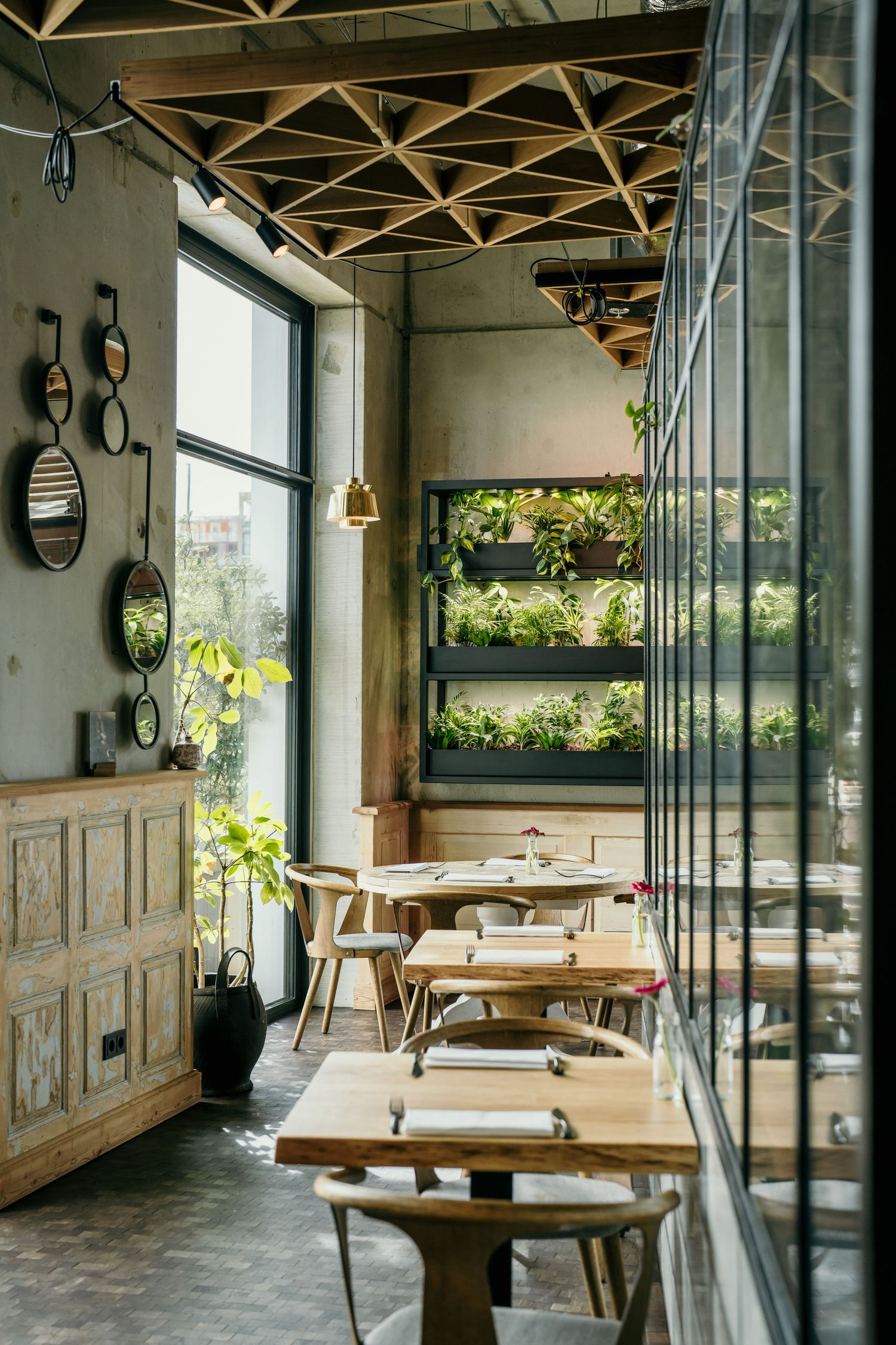 Modern restaurant interior with wooden furniture and vertical garden wall features.