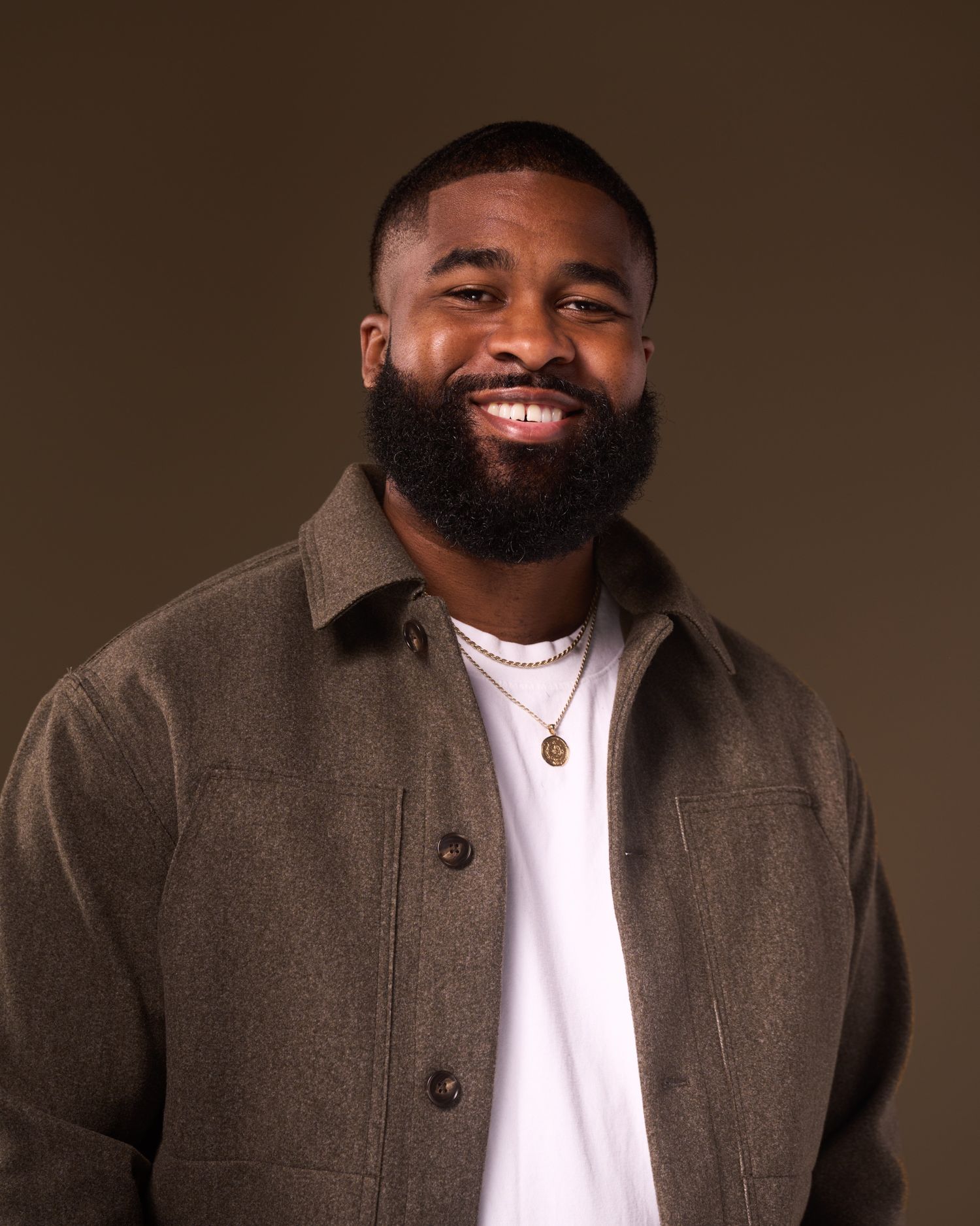 Professional portrait series of someone in a gray jacket and white shirt against dark background.