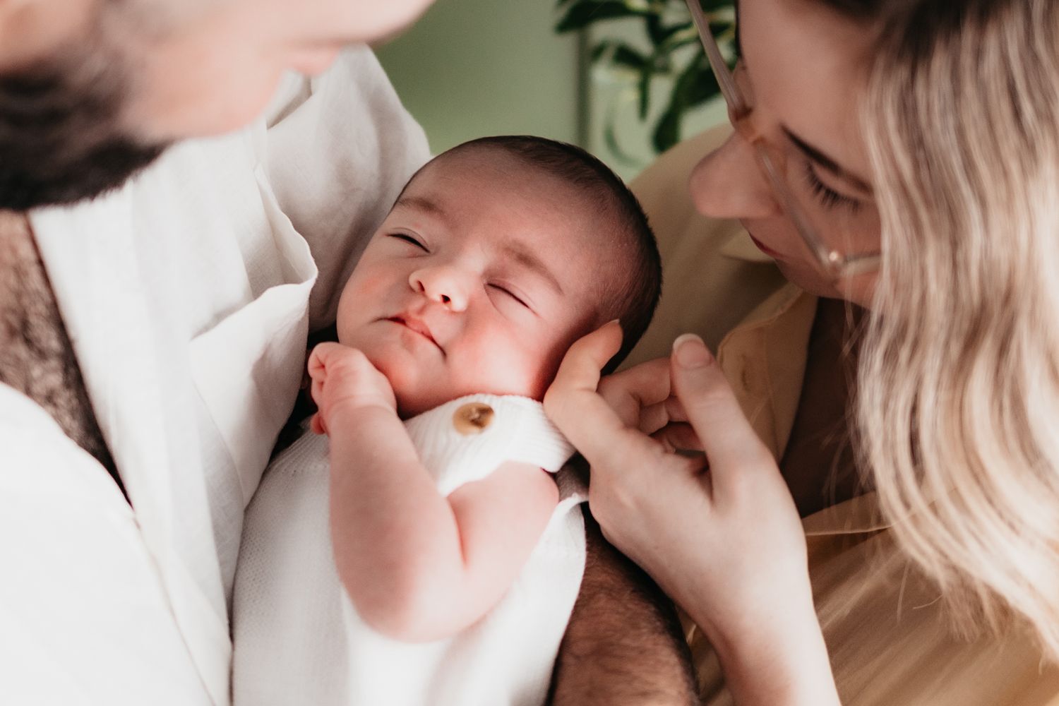 Newborn photoshoot in their home nursery in the arms of her mother and father