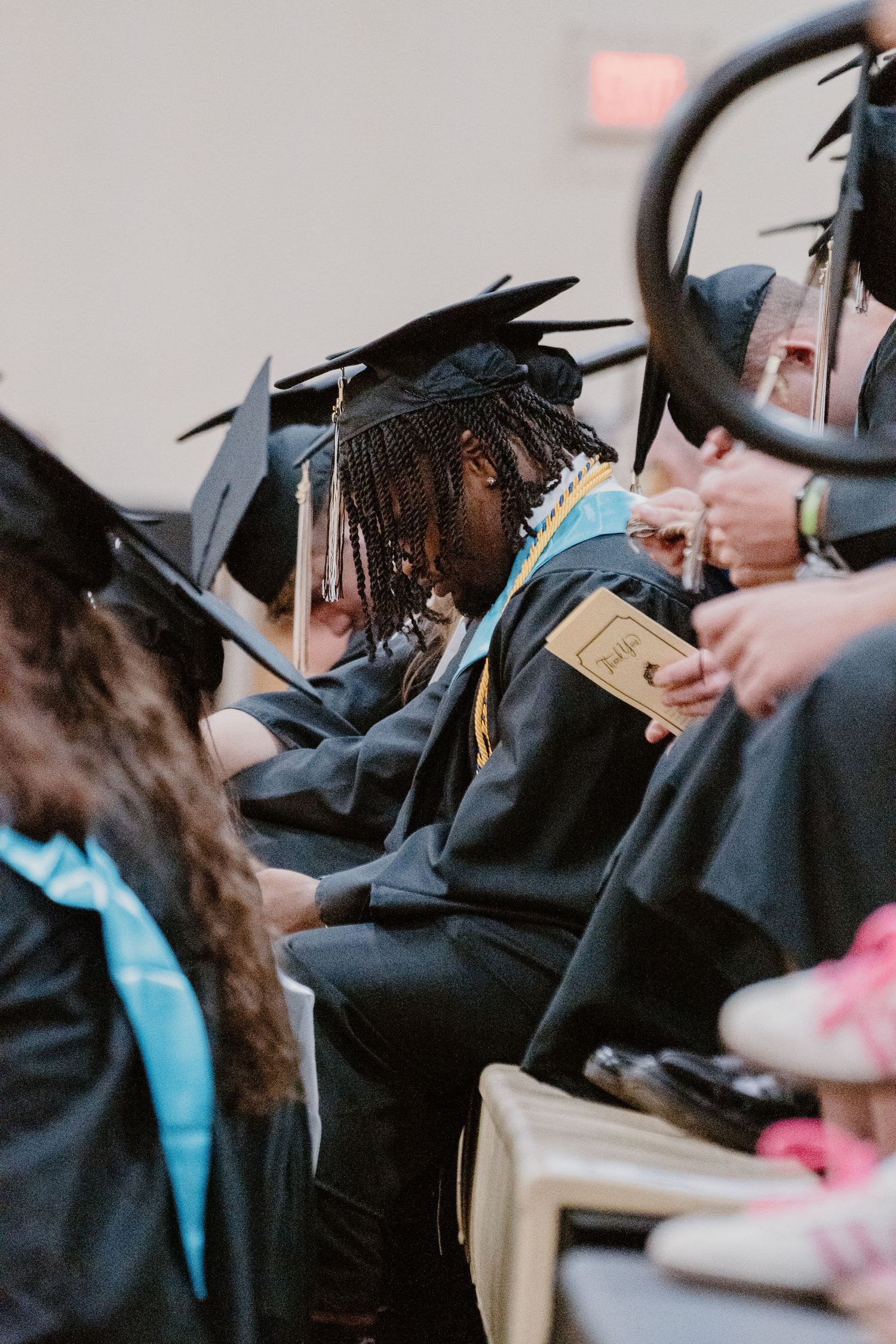 Graduates in black caps and gowns seated during commencement ceremony.