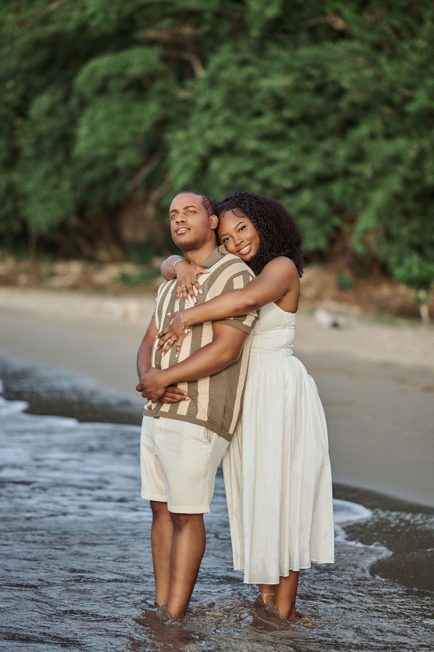 A couple holds hands while standing in shallow turquoise ocean water, by Jamaica Wedding Photographer