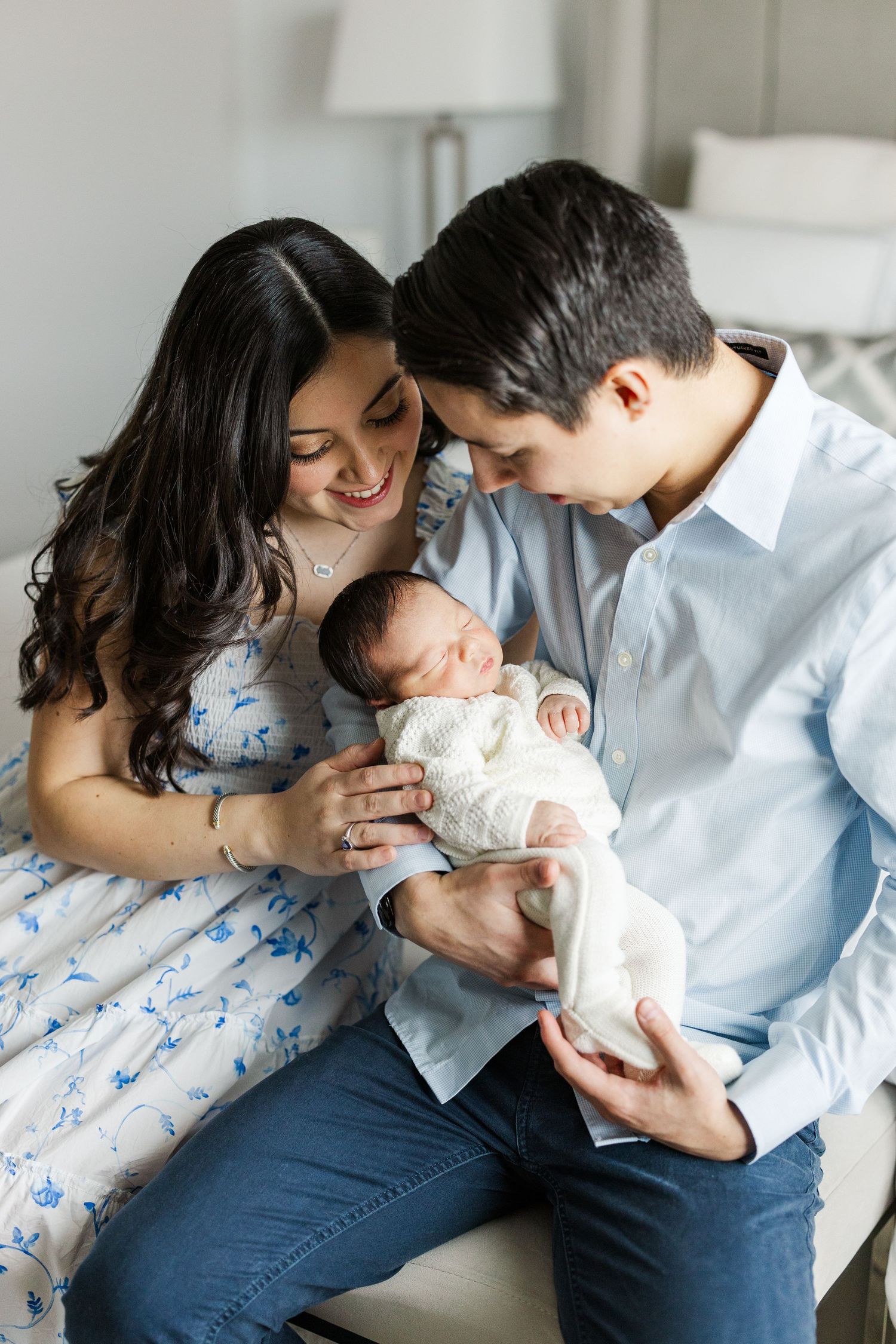 Family shares intimate moment with newborn baby on bed.
