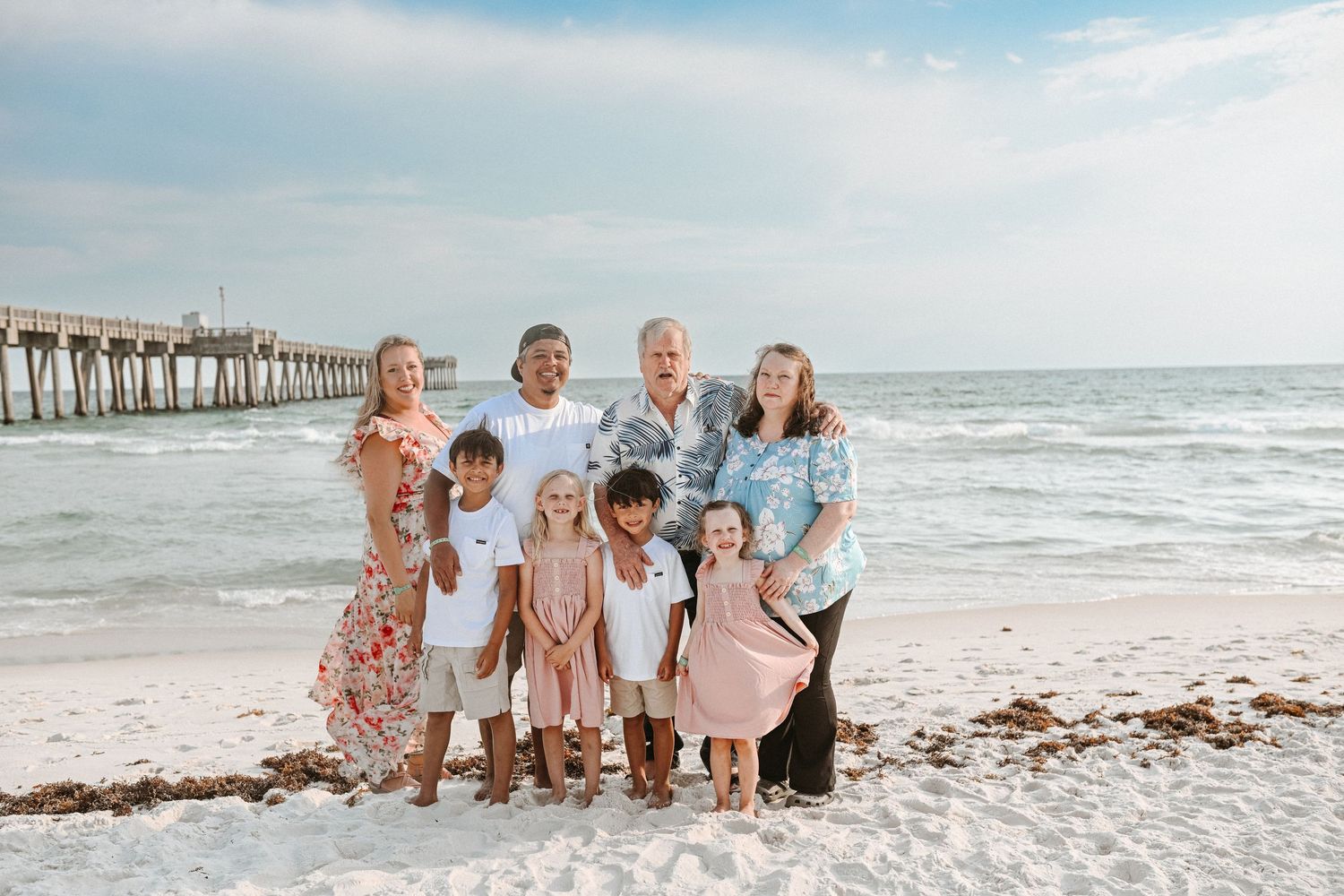 Extended family group wearing coordinated outfits for beach portrait session.