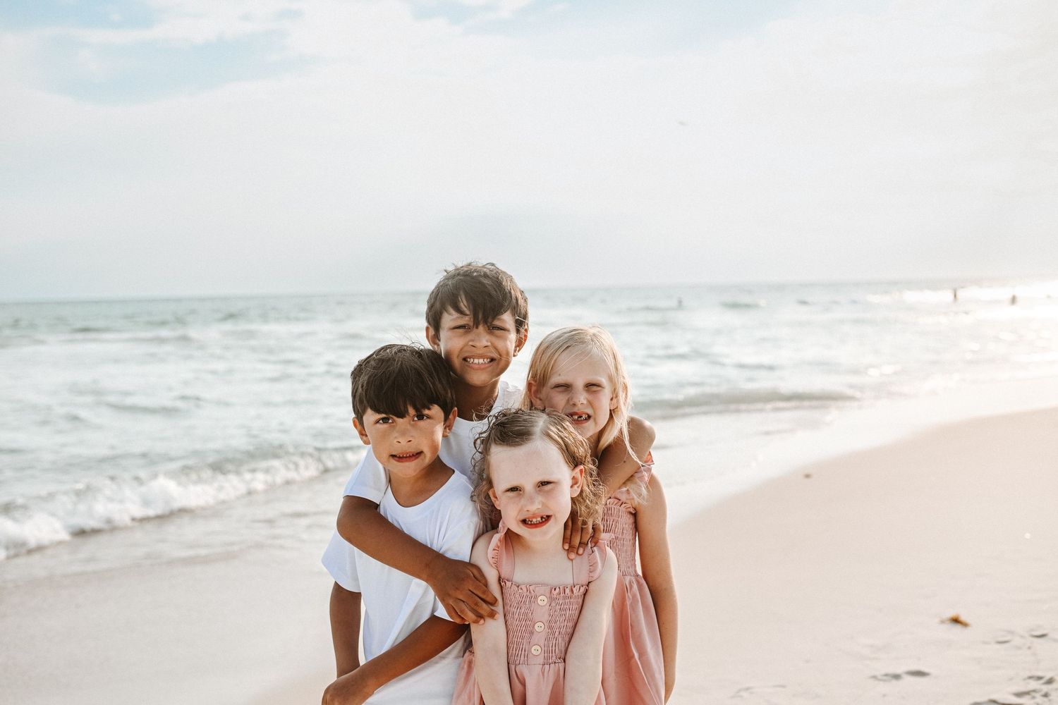 Children share joyful moment together on sunny beach shoreline.