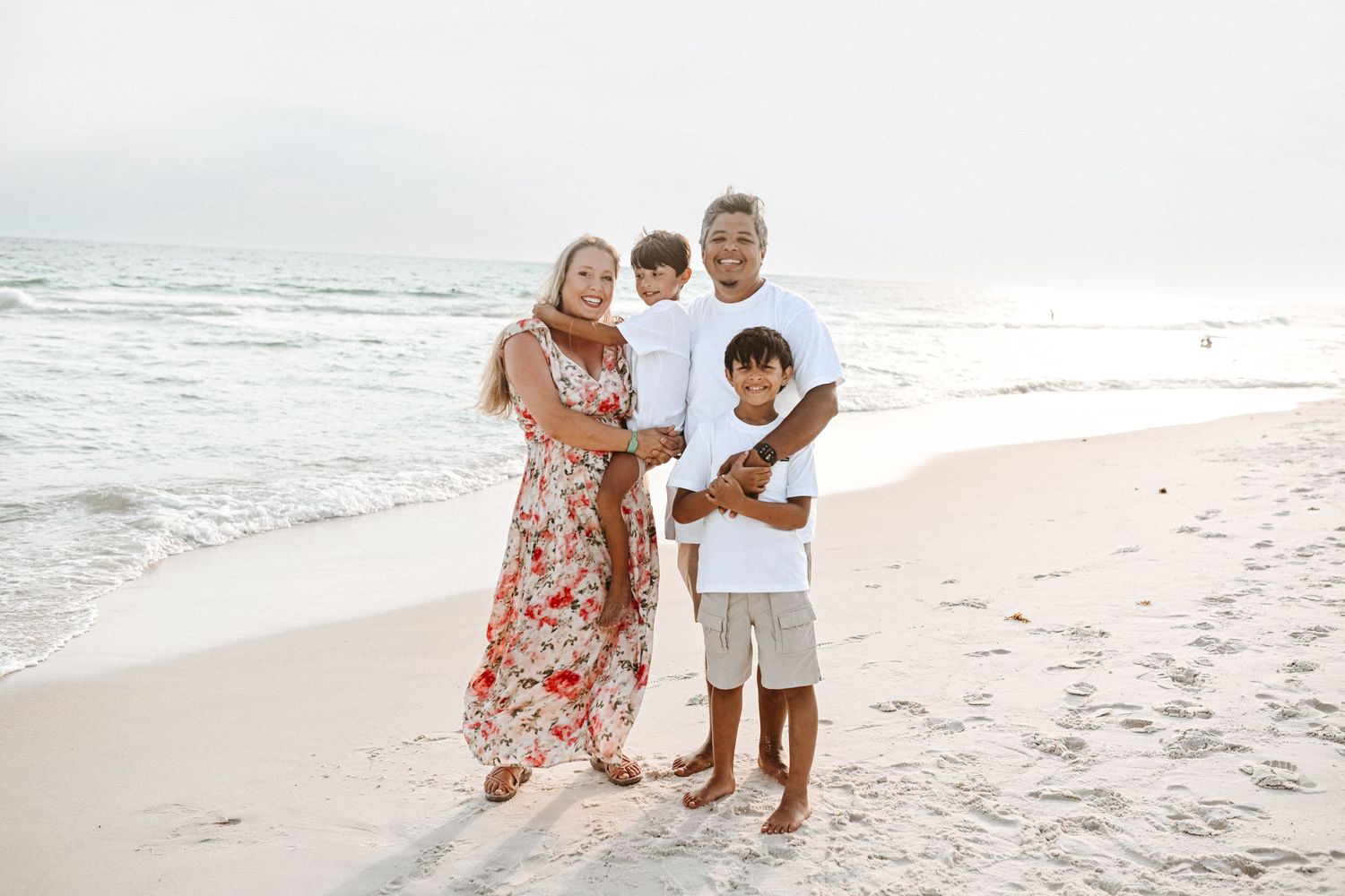 Family members gather for casual photos on sunny beach.