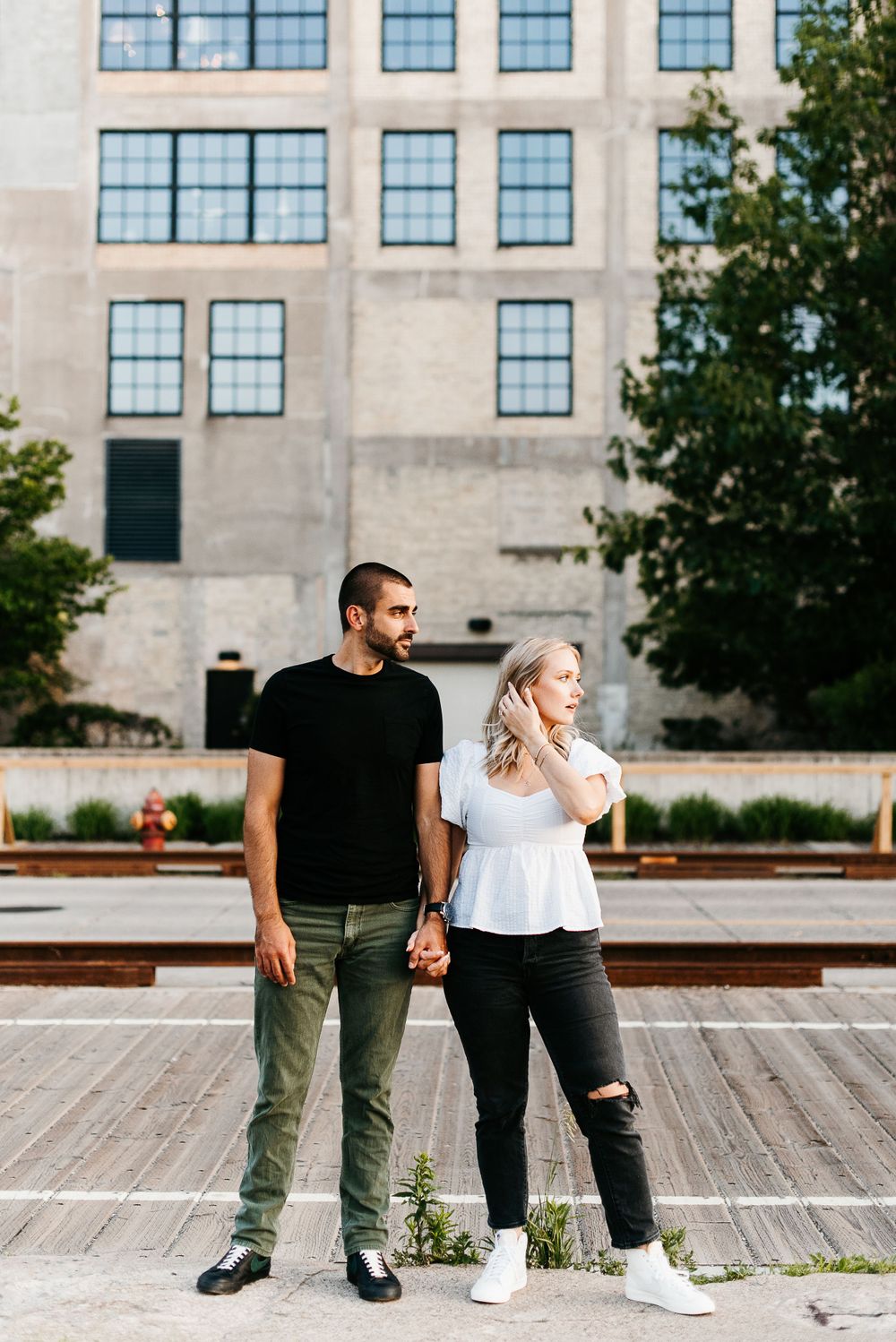 A couple standing next to each other, both looking off to the right of the frame, wearing casual clothing in Minneapolis, Minnesota.