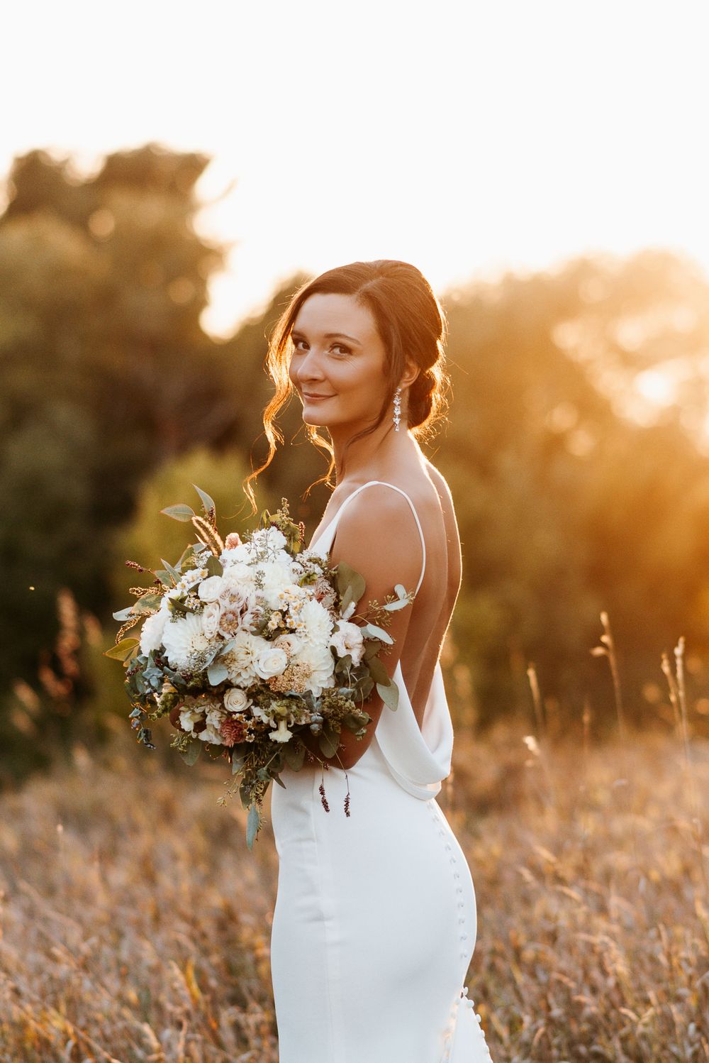 A bride holding her bouquet during sunset at 45th Parallel in Wisconsin. Lindsay Miller Photography
