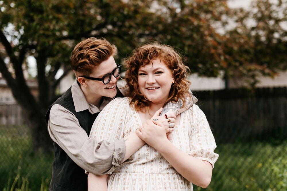 A LGBTQ+ couple embracing and holding each other in front of a large tree in Saint Paul, Minnesota. Lindsay Miller Photography