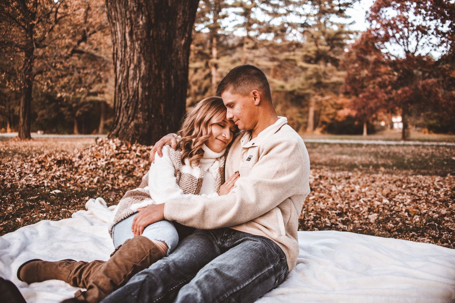 A cozy autumn portrait on a blanket surrounded by fallen leaves.